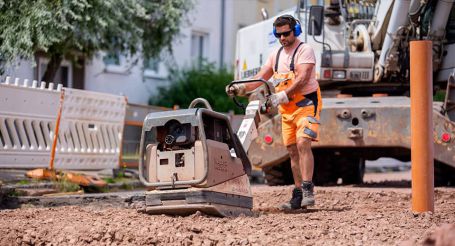 Mitarbeiter verdichtet mit einer Rüttelplatte den Untergrund auf einer BGB-Baustelle